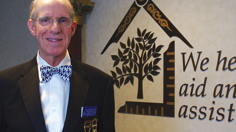 Senior male in suit and bow tie, smiling at camera.