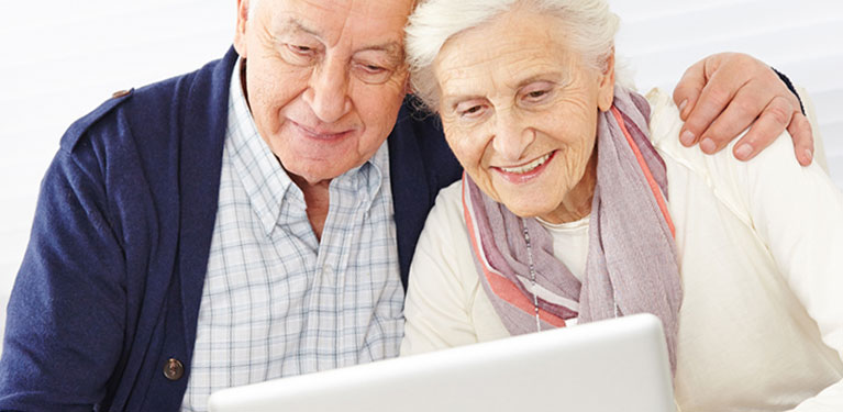 Senior man and woman looking at computer screen.