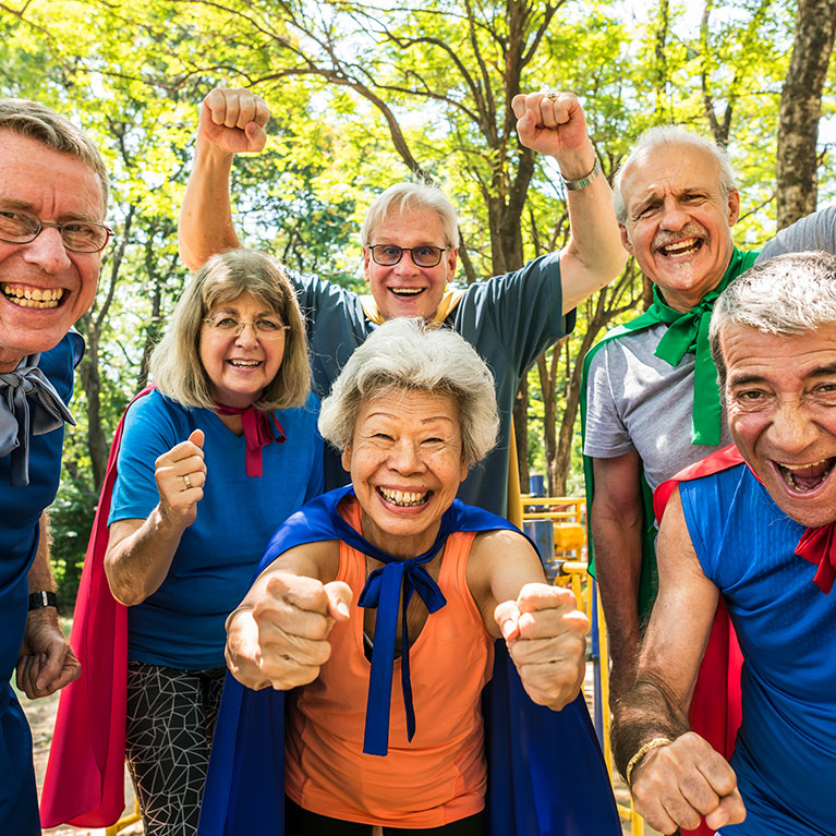 Group of older people smiling and celebrating wearing capes