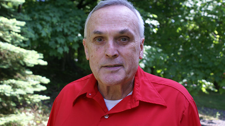 Senior man in red shirt smiling.