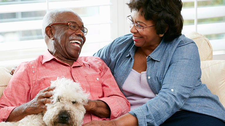 Senior couple laughing while sitting with a dog.